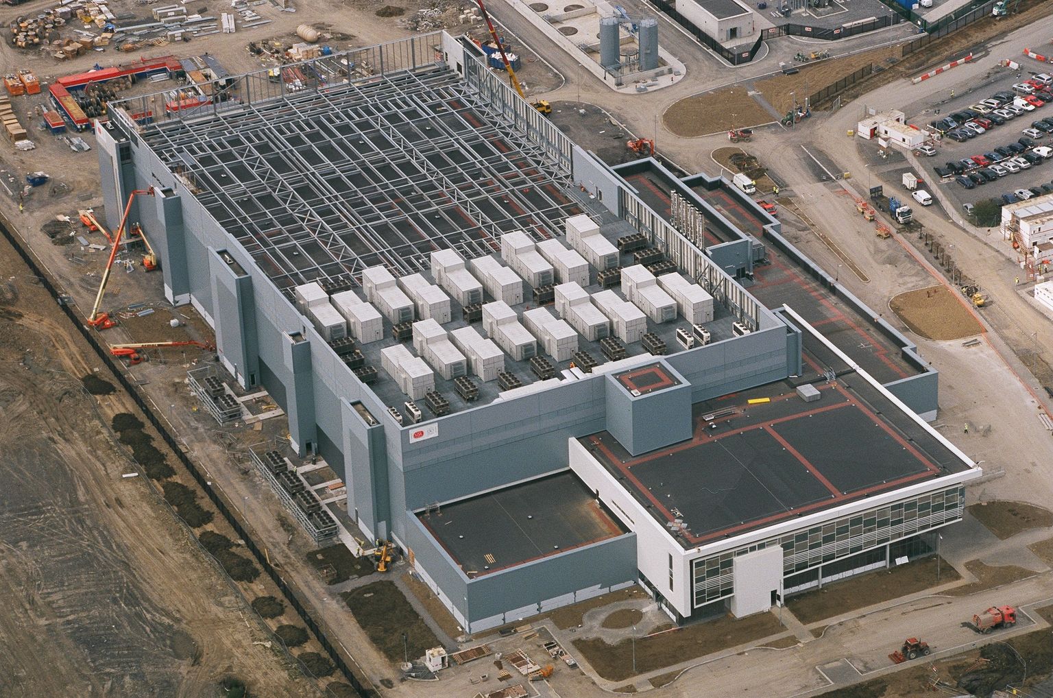 Architectural reference: an aerial view of a data centre under construction in Dublin, with exposed steel framing and rooftop cooling equipment